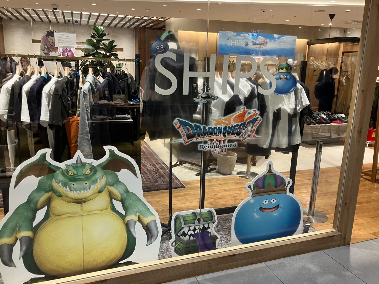 IMG_3875 - innovaTopia Storefront display with Dragon Quest characters and monsters (yellow dragon, blue slime, and others) on glass windows in a clothing store.