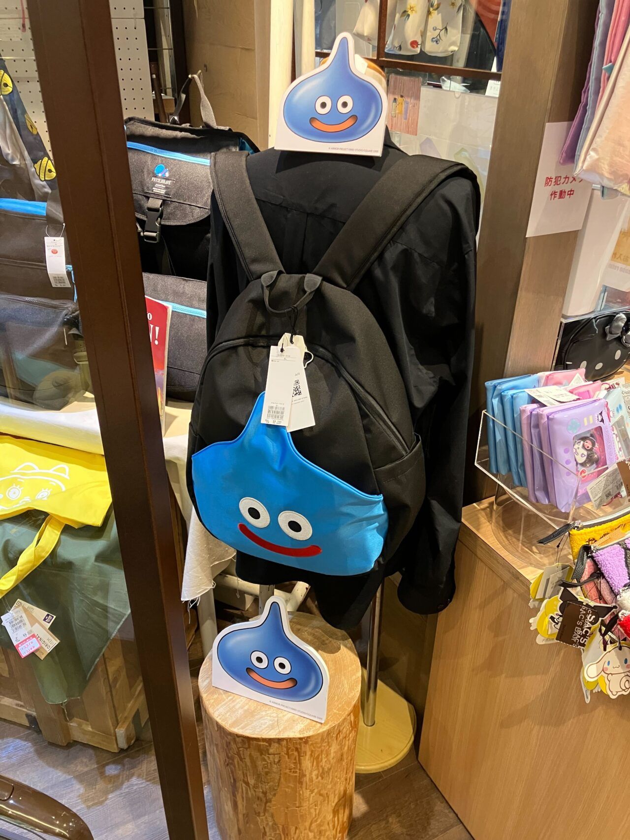 IMG_3984 - innovaTopia Black-clad mannequin wearing a blue slime-shaped crossbody bag with a smiling face, in a store display.