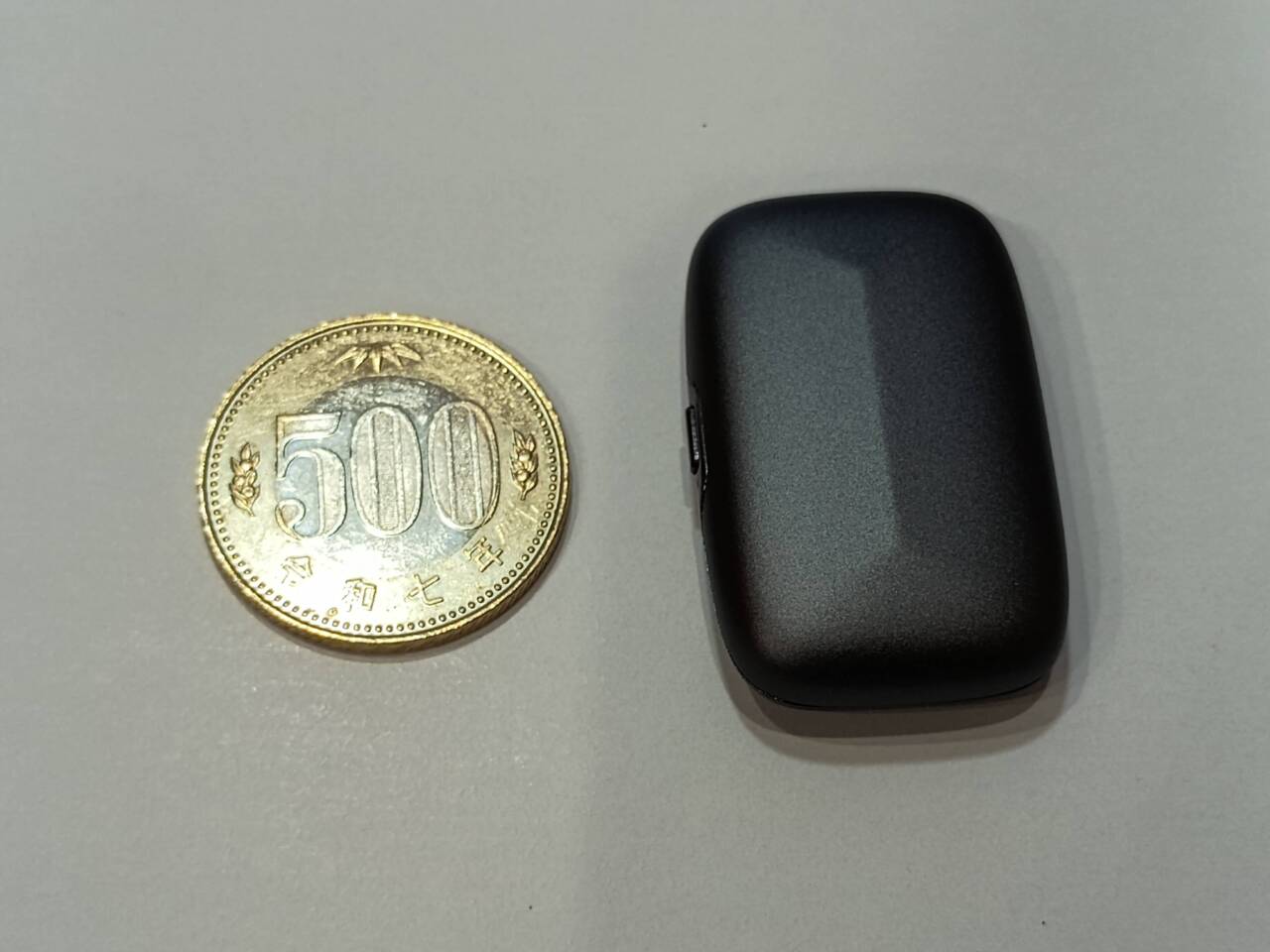 500円硬貨の隣に置かれたMemoket Gem本体。硬貨よりひと回り大きい程度の、角の丸い長方形の小型機器
